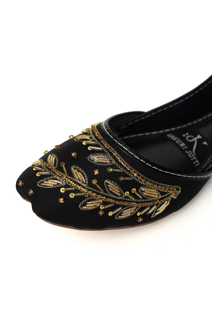 Closeup of Onyx Vine black Kasuri Jutti with luxurious golden vine embroidery