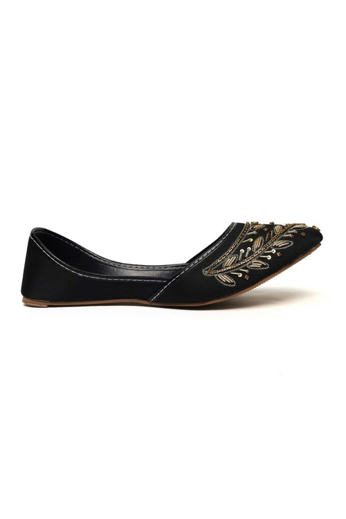 Black flat kasuri jotti shoe with gold embellishments on a white background