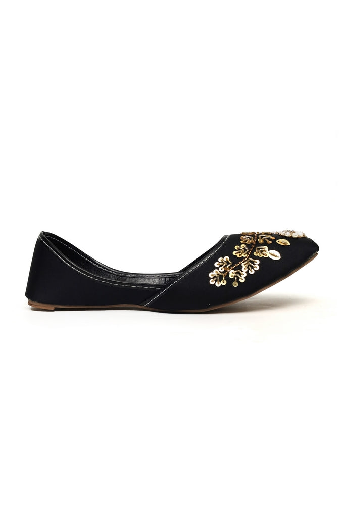 Black flat kasuri jutti and punjabi shoe with gold floral embroidery on a white background
