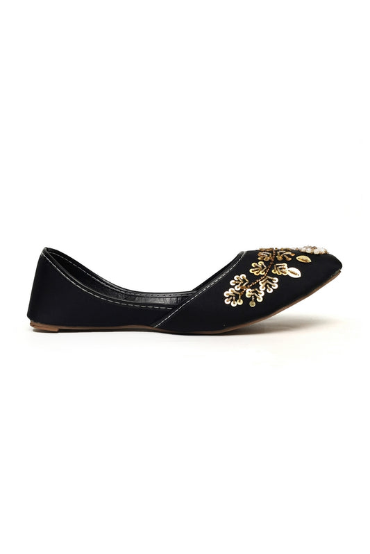 Black flat kasuri jutti and punjabi shoe with gold floral embroidery on a white background