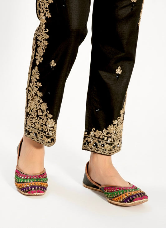 Black pants with gold embroidery and colorful Black Phulkari Kasuri Jutti on a white background
