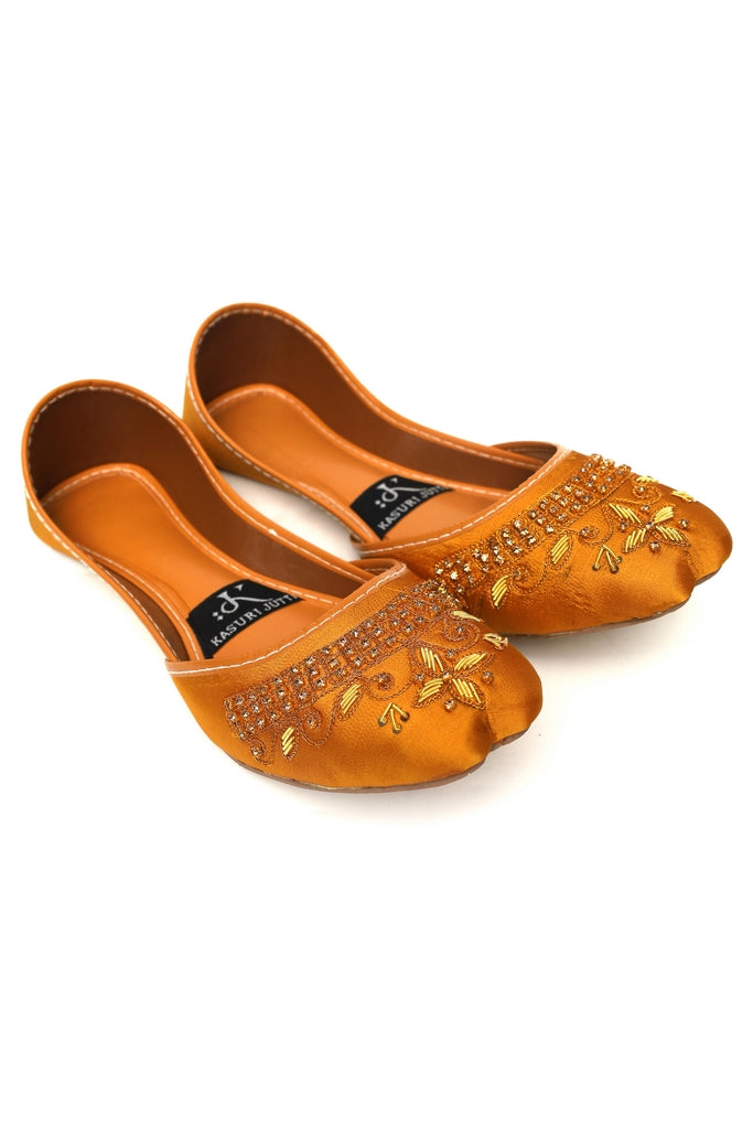 Pair of gold embroidered yellow kasuri jutti on a white background, front pic