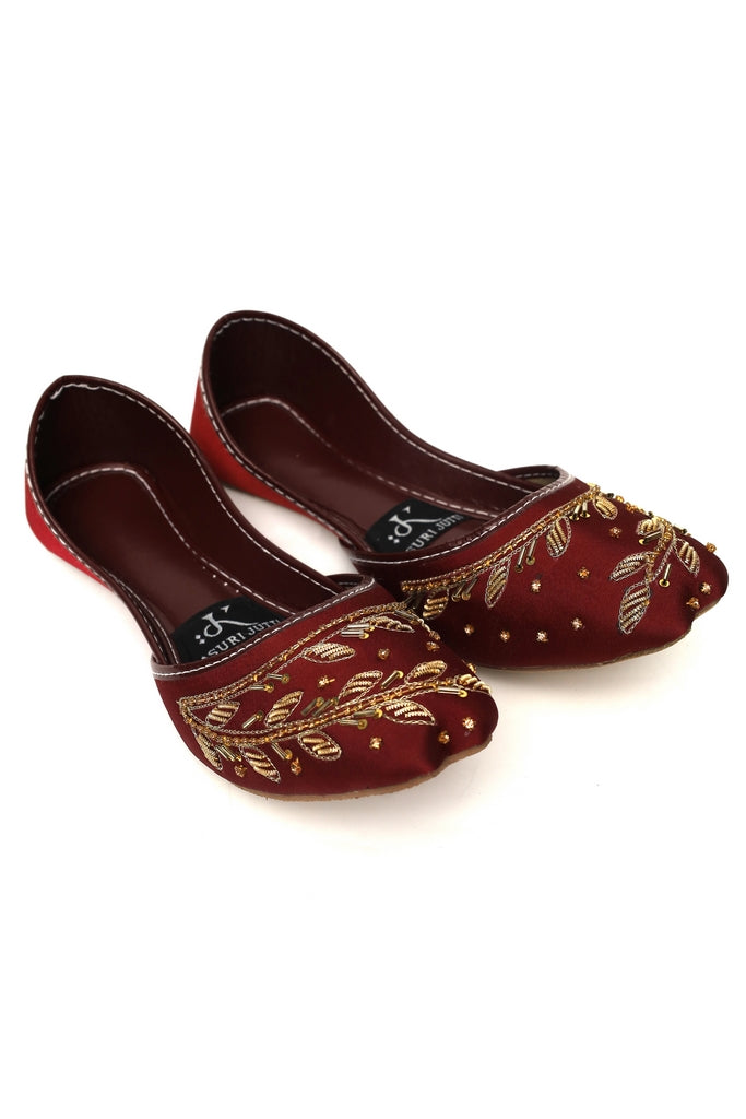Pair of maroon Ruby Ember Kasuri Jutti embroidered shoes on a white background, front angle
