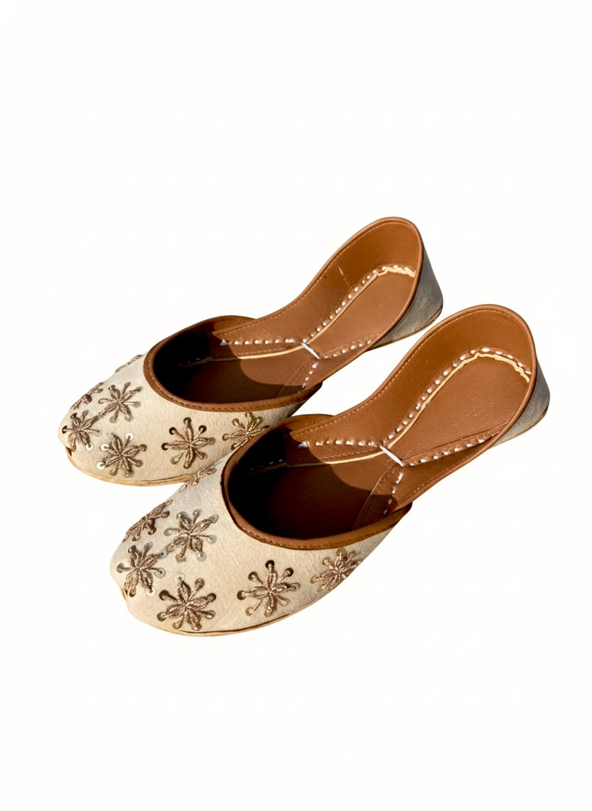 Pair of Tilla Work Kasuri Jutti with floral patterns on a white background