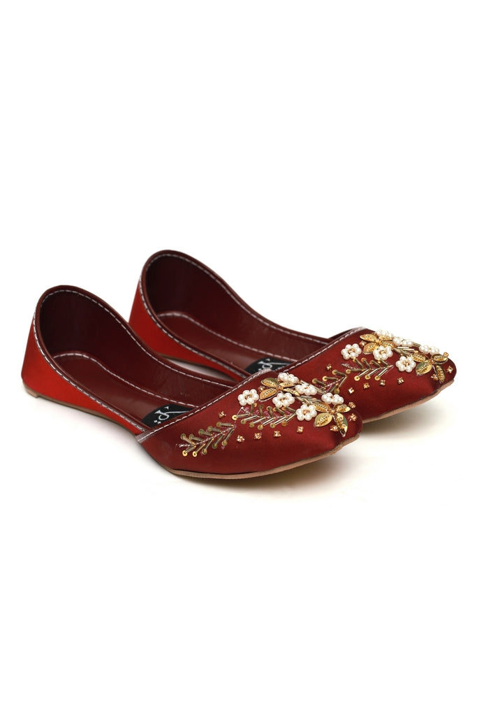 Pair of red maroon Kasuri jutti with floral embroidery on a white background