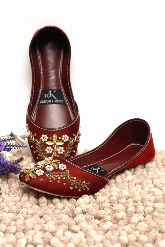 Maroon blossom embroidered Kasuri Jutti with gold zari work – one shoe standing, one lying flat