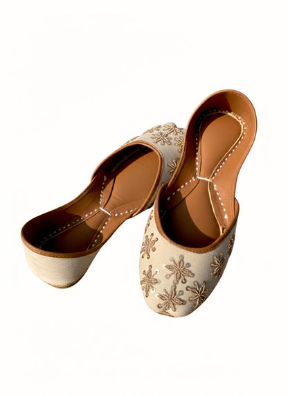 Cream Kasuri jutti with intricate gold tilla thread floral embroidery, shown from side angle