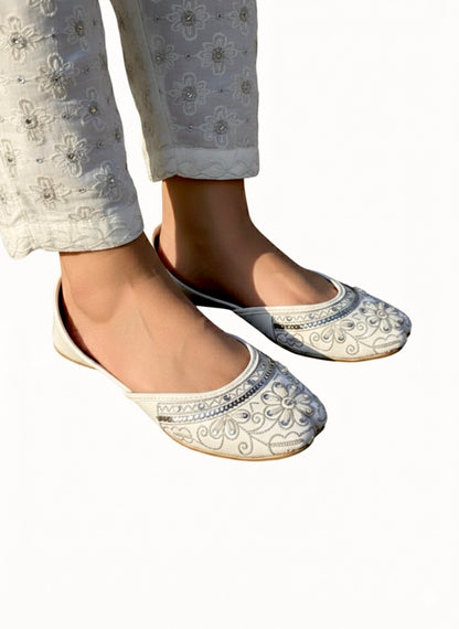 White Kasuri jutti with silver work worn on feet with white trouser